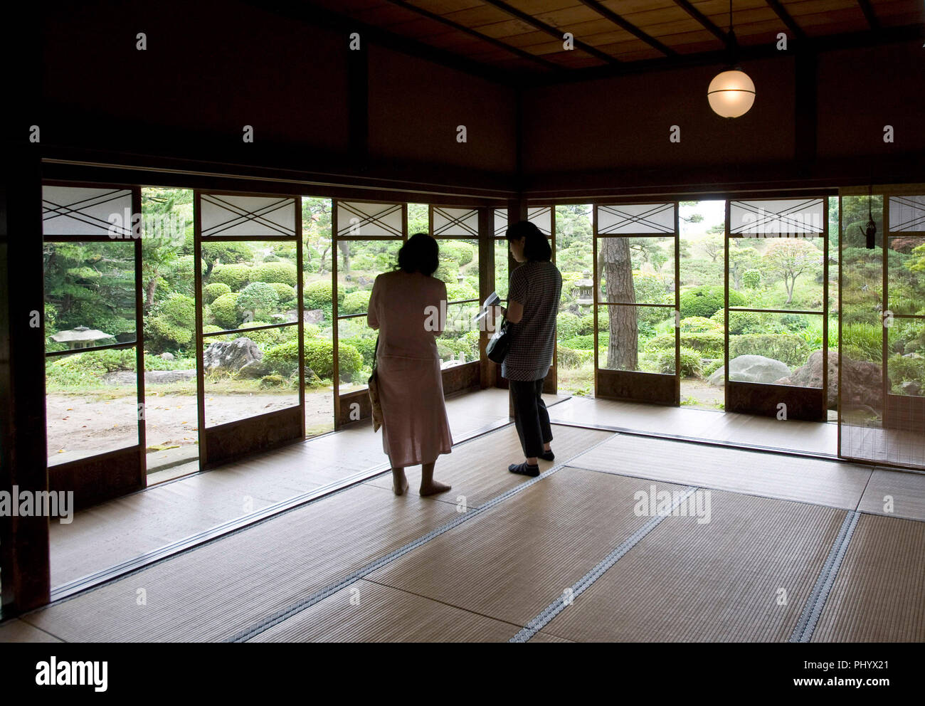 Visitors admire the Kakubuen garden from the first floor reception room of the main building of the Honma Museum of Art in Sakata, Yamagata Prefecture Stock Photo