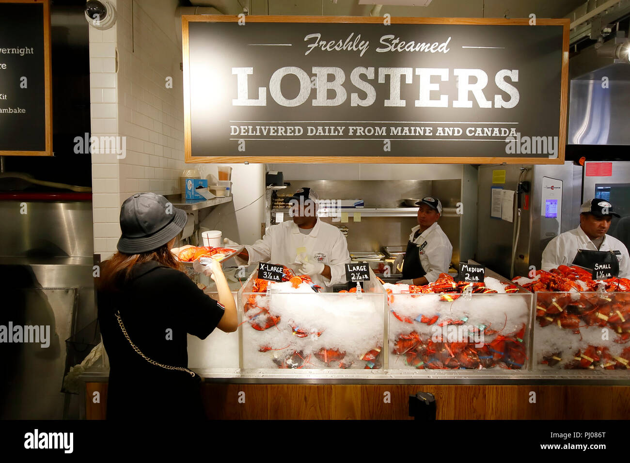 A customer receives a freshly steamed lobster at the Lobster Place inside the Chelsea Market, New York, NY. Stock Photo