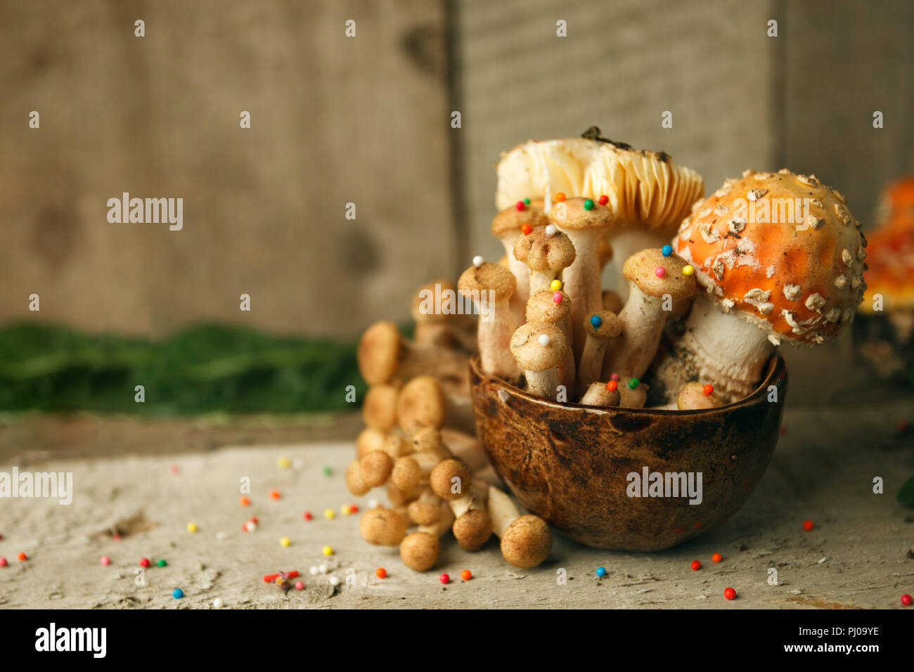 Magic fairytale party table decor, mushroom with confectionary in cup on wooden background, poison toxic food Stock Photo