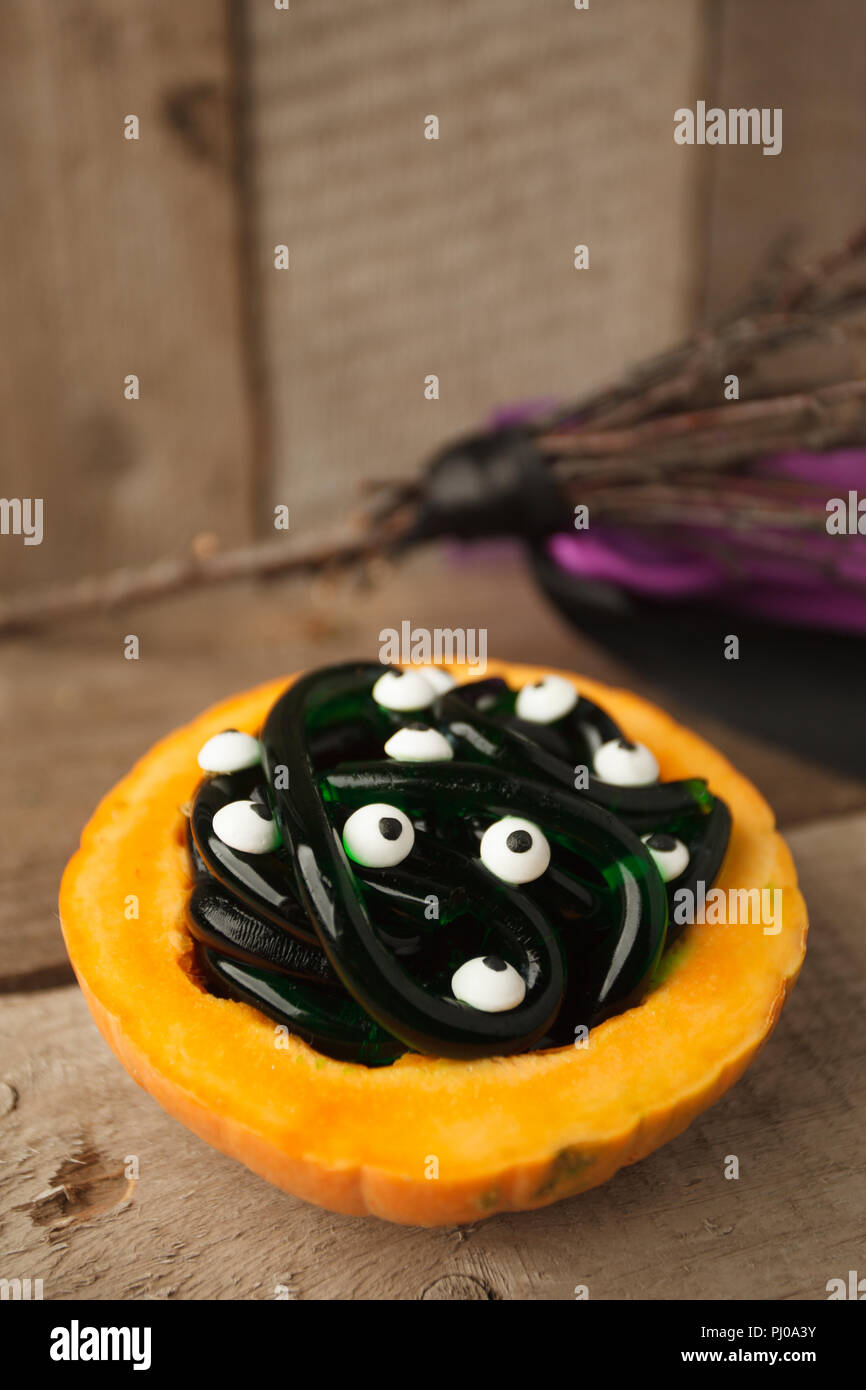 Pumpkin and gummy worms with eyes candy on wooden background. Halloween
