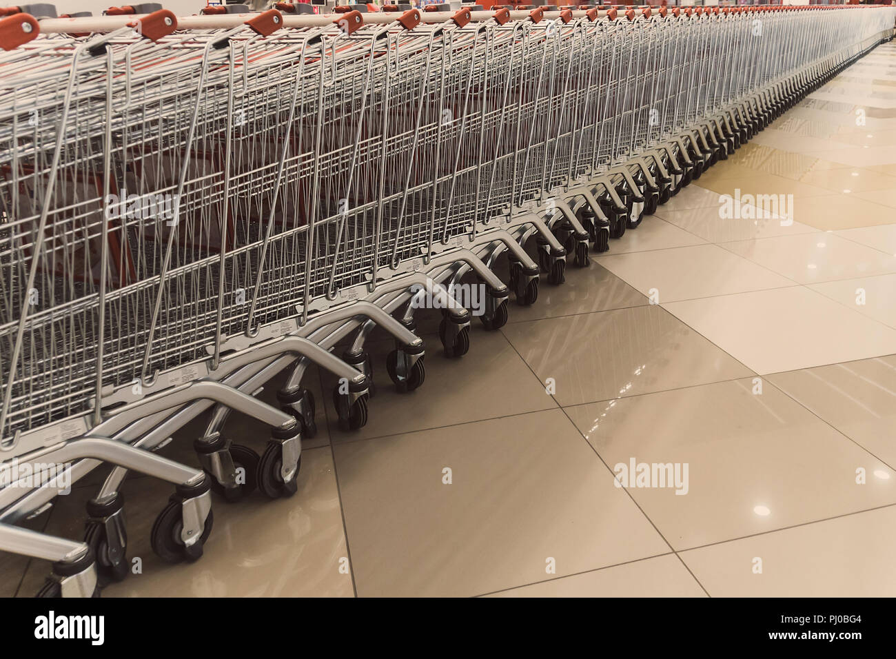 Many rows of red shopping carts outside by store with closeup by parking lot. Inside a large supermarket. Modern and stylish shopping Mall. Grocery st Stock Photo