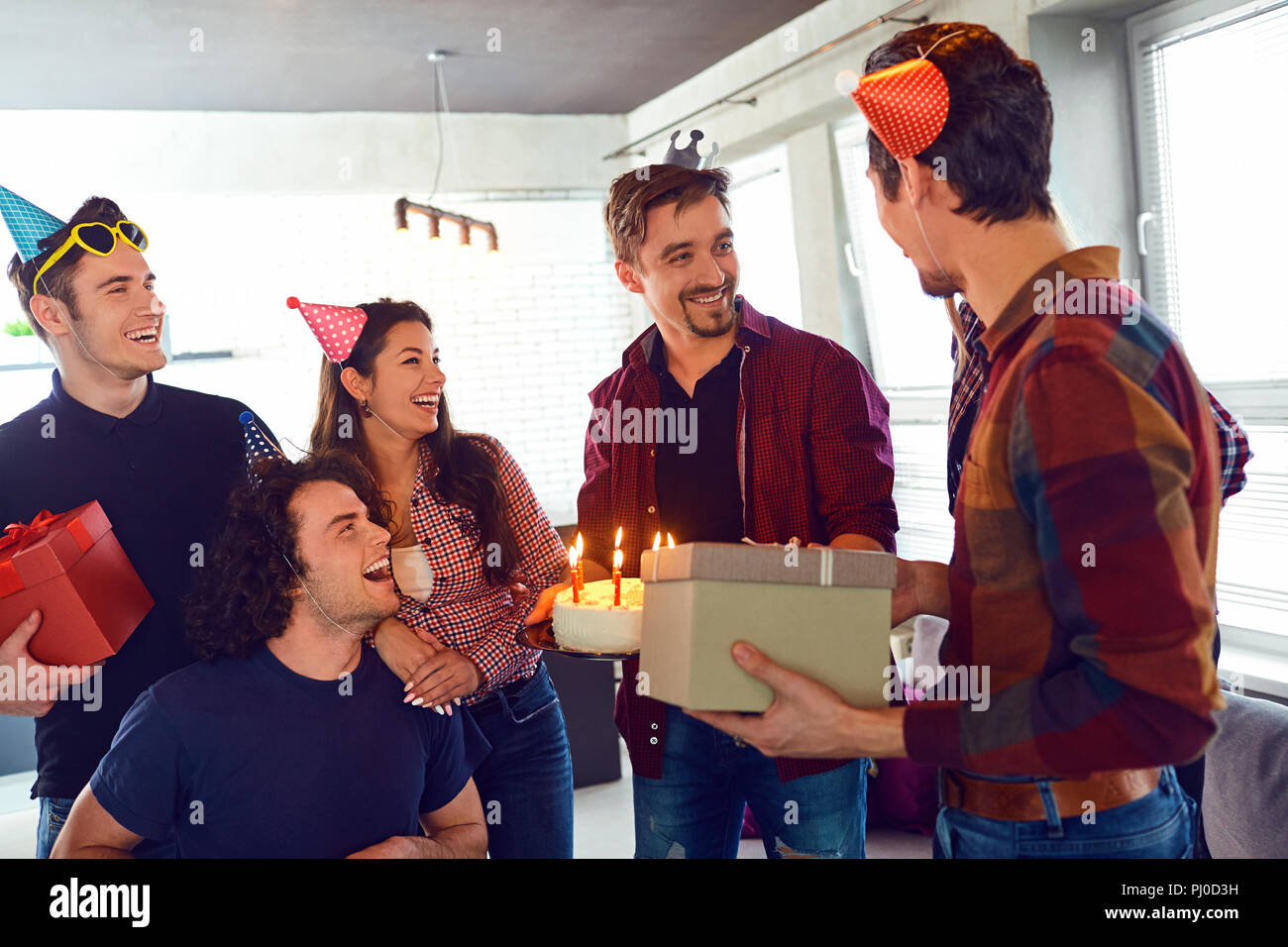 Friends with cake with candles celebrating birthday at a party. Stock Photo