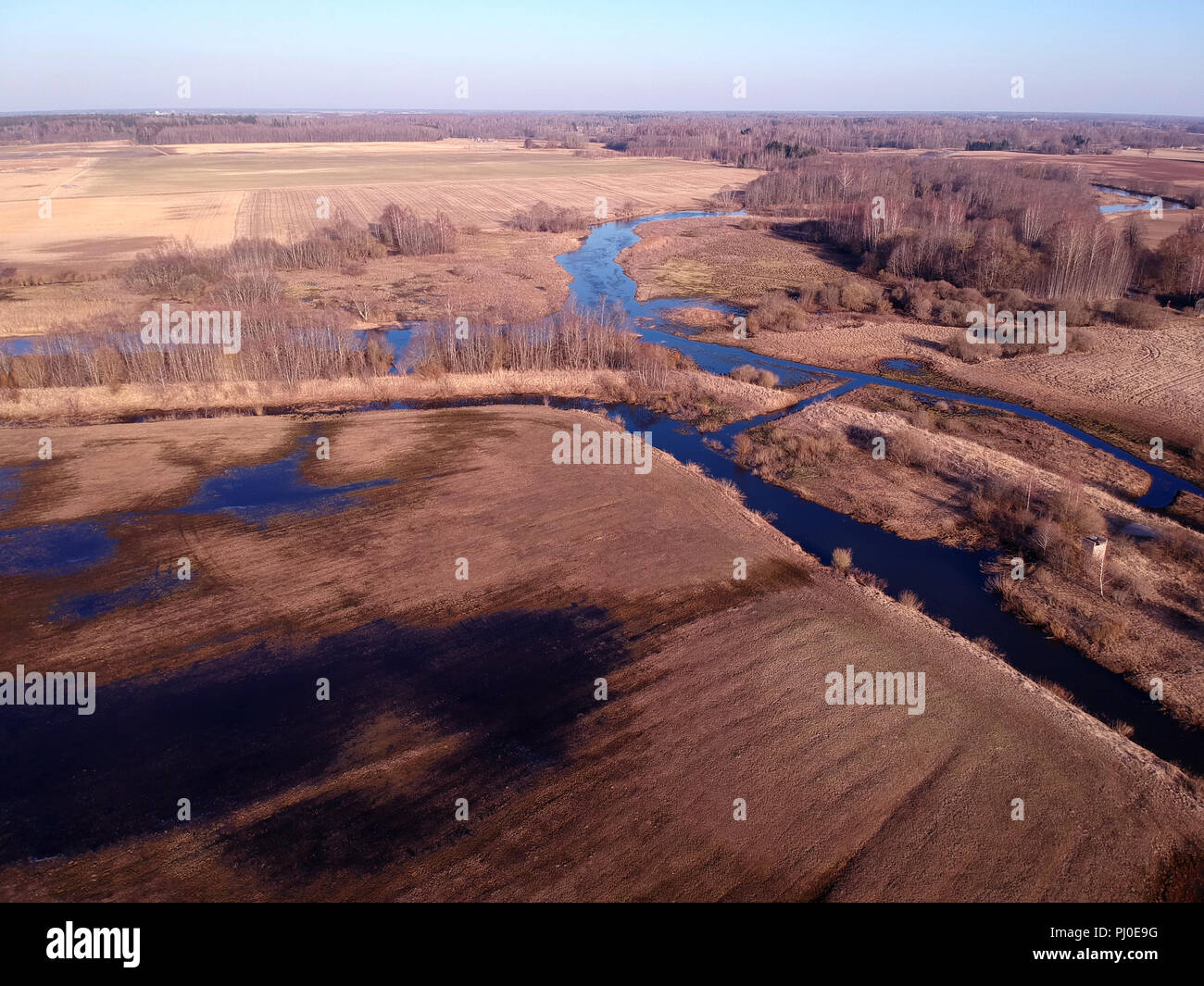 Early spring meadows and bushes near river and water flood, aerial view Stock Photo