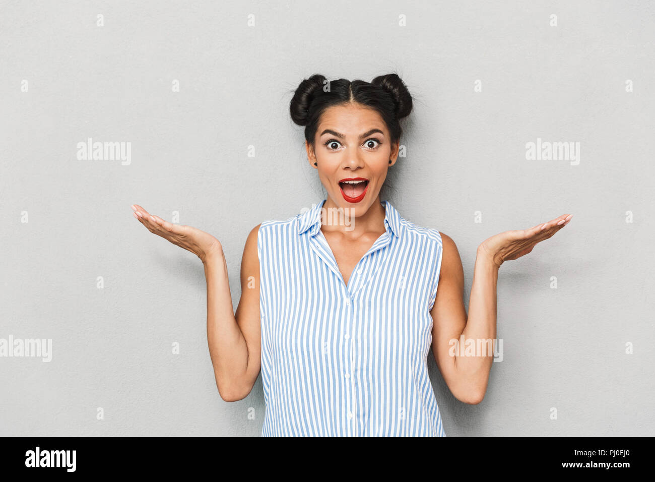 Portrait of a cheerful young woman shrugging shoulders isolated Stock Photo