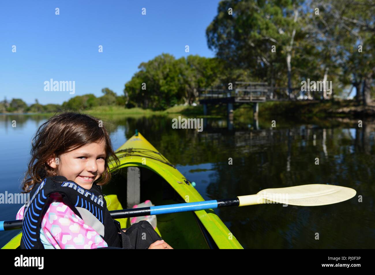 Young girl smiling while sitting in a canoe on a lake, Ross River QLD