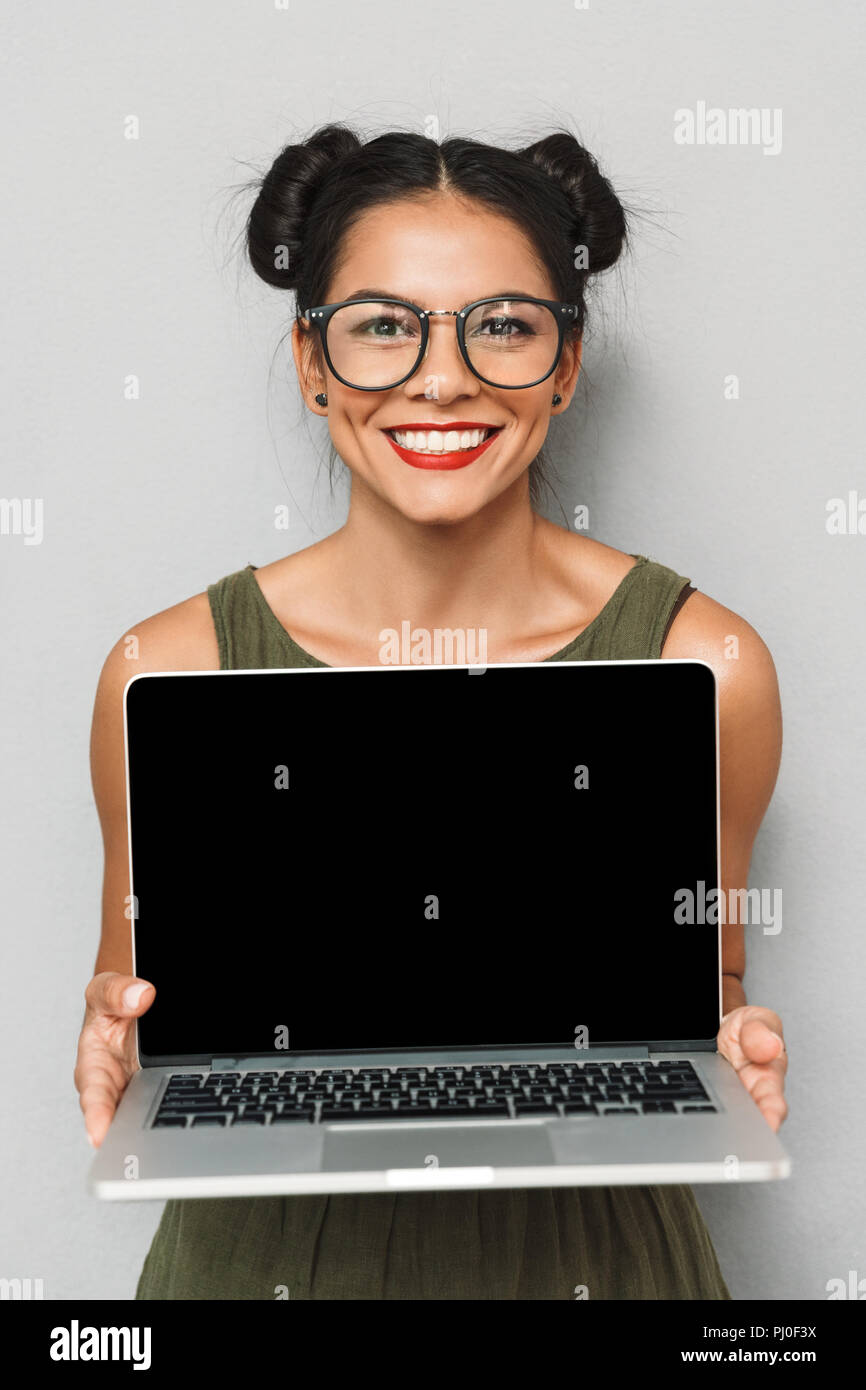 Portrait of delighted young woman isolated, showing blank screen laptop ...