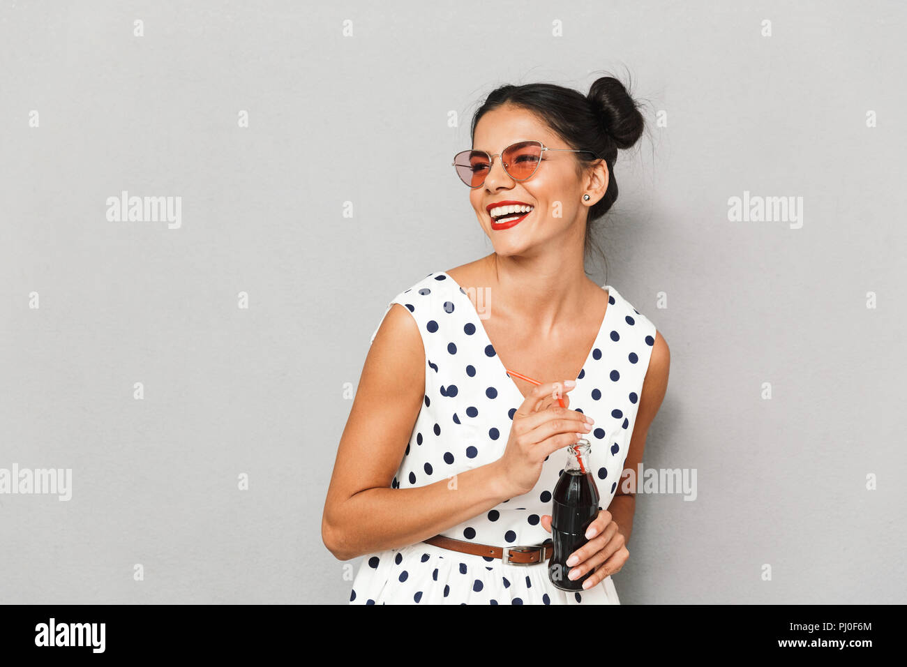 Fizzy Looking Portrait of a happy young woman in summer dress and sunglasses isolated ...