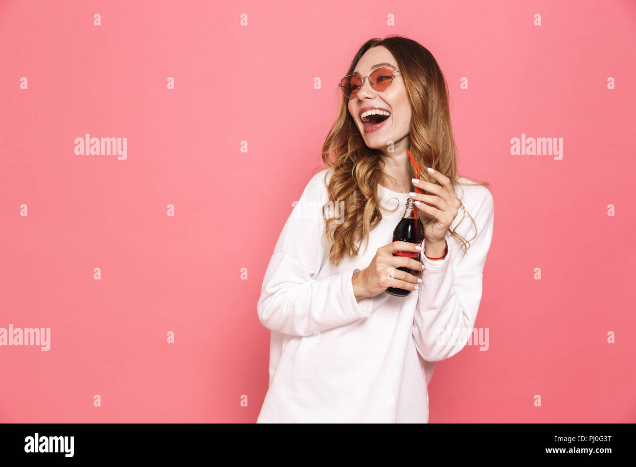 Fizzy Looking Portrait of a cheerful young woman in sunglasses drinking fizzy drink ...