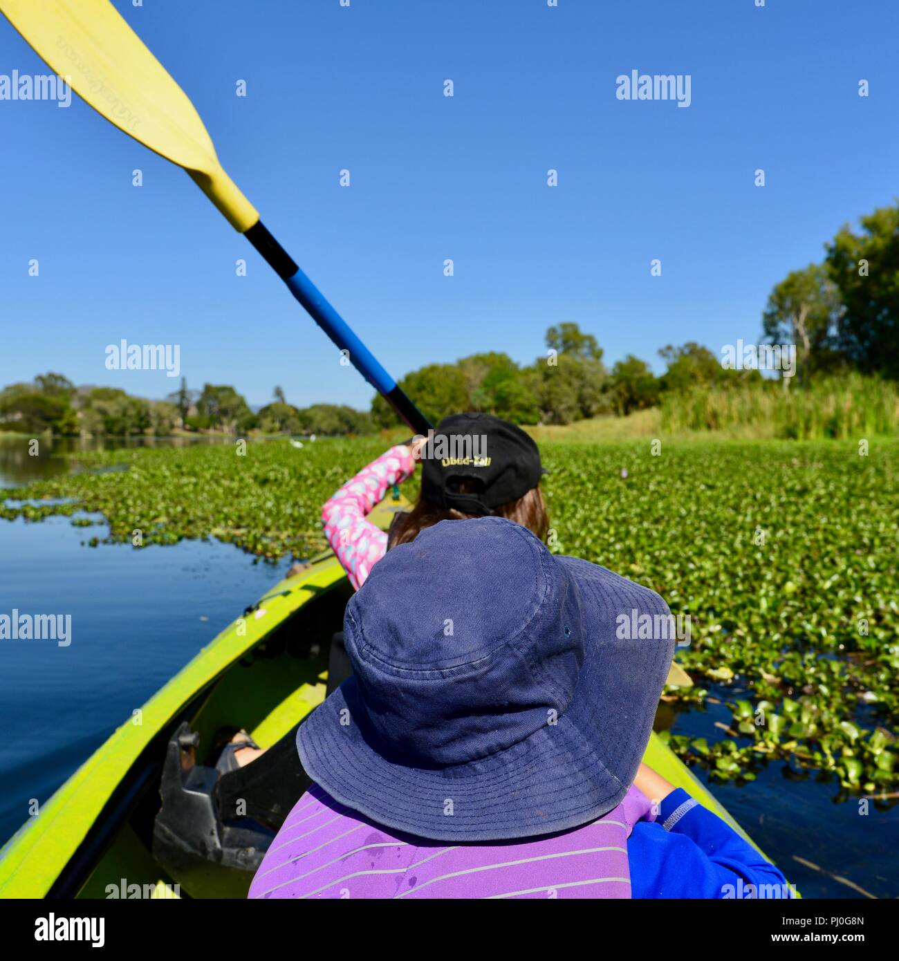Children paddling in a canoe in beautiful weather, Ross River QLD