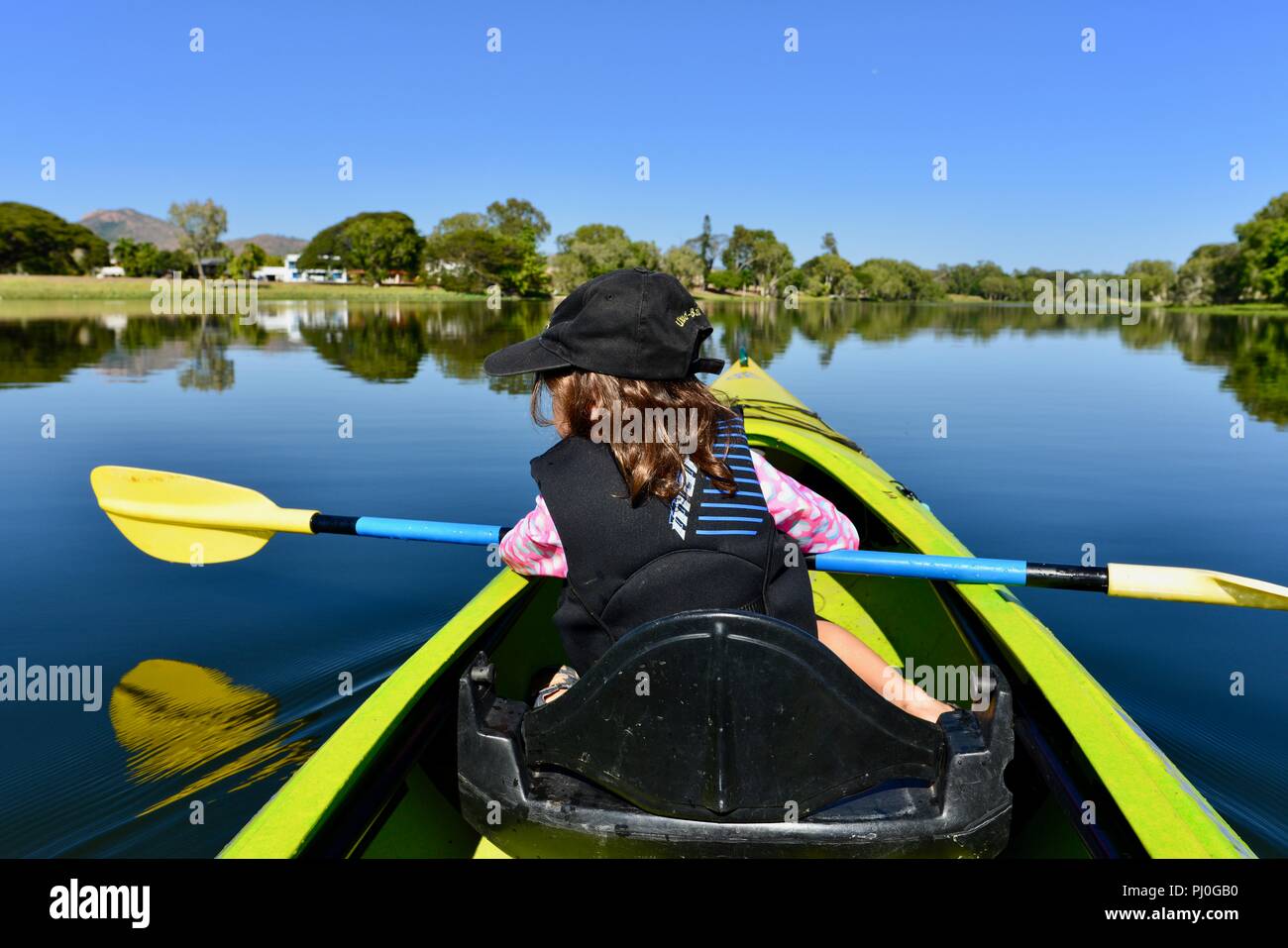 Children paddling in a canoe in beautiful weather, Ross River QLD