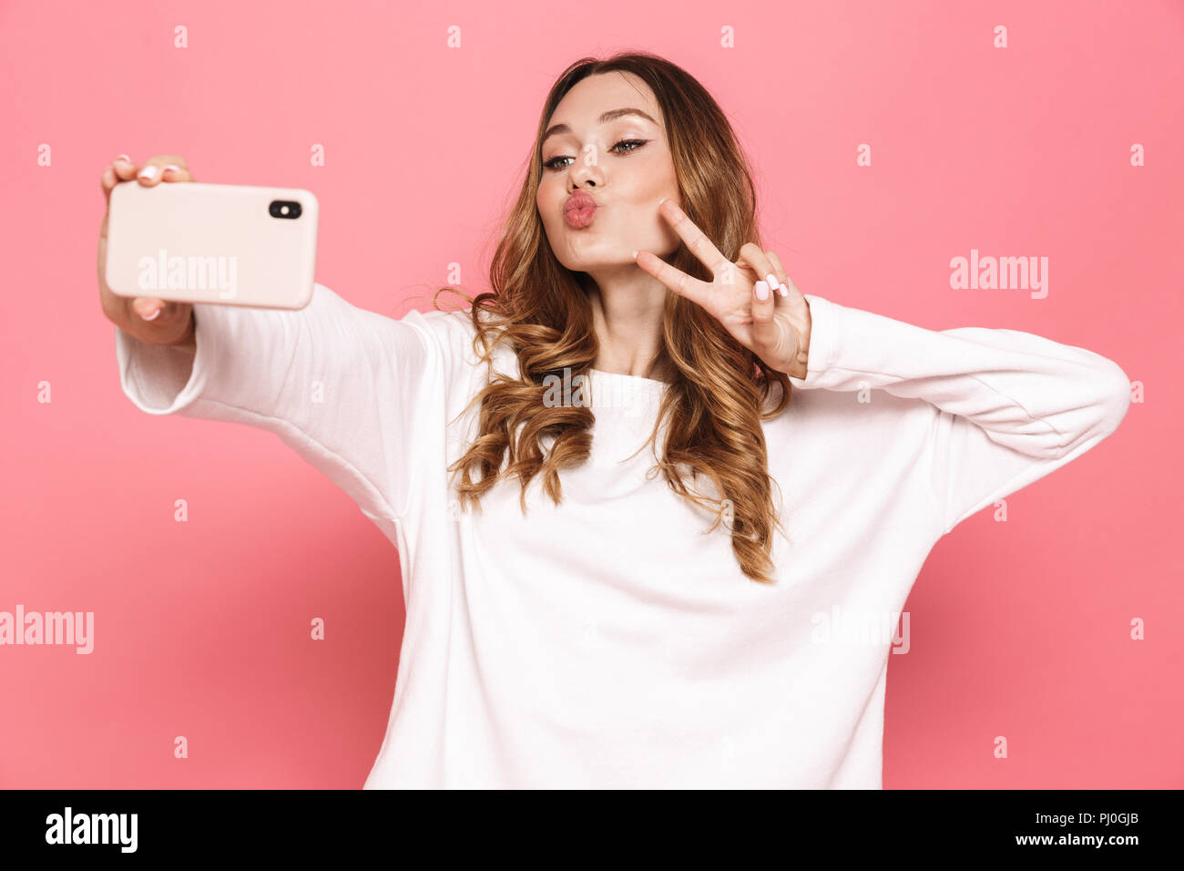 Portrait of a happy young woman taking selfie with mobile phone ...