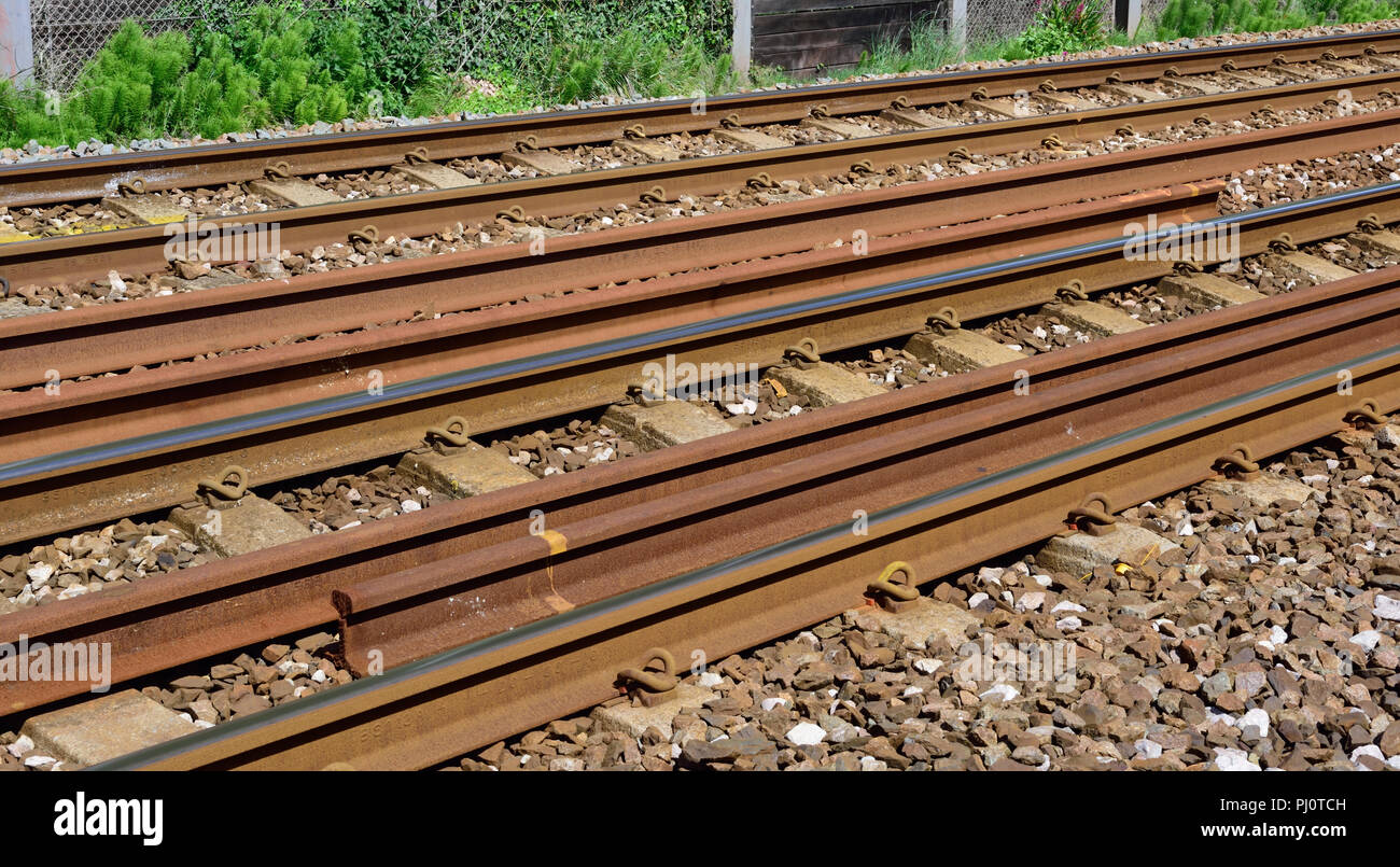 Spare long-welded rails stored between the running lines. Stock Photo