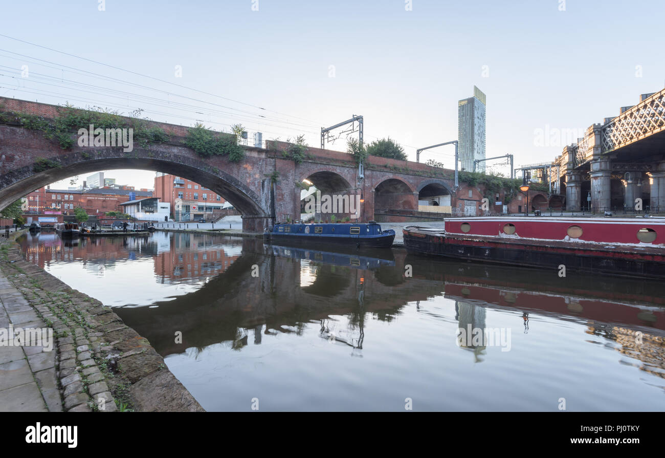 View from the towpath beside the Bridgewater Canal to the Castlefield Viaduct bridge and the Hilton Hotel in Manchester Stock Photo