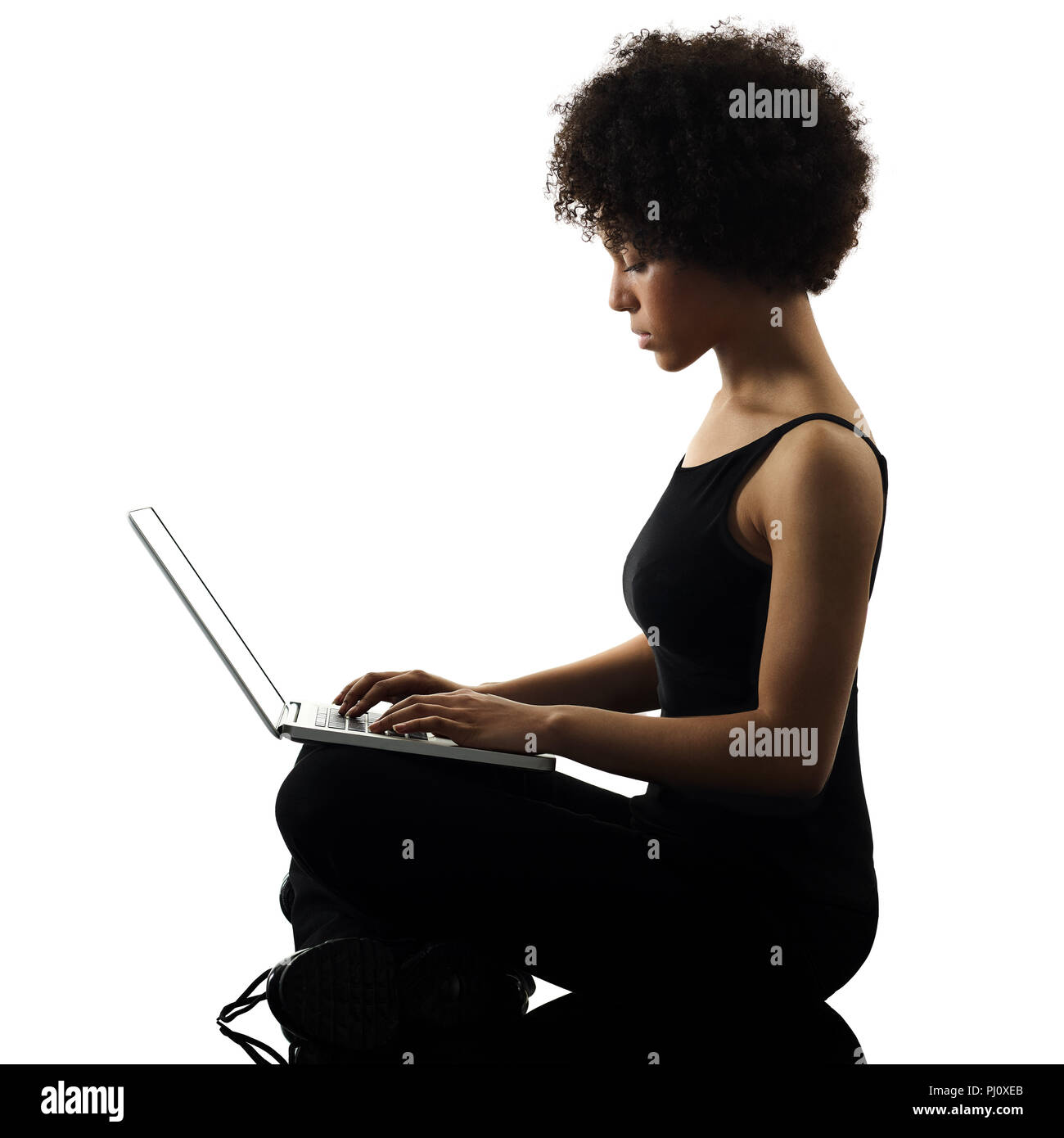 one mixed race african young teenager girl woman computer laptop in studio shadow silhouette isolated on white background Stock Photo