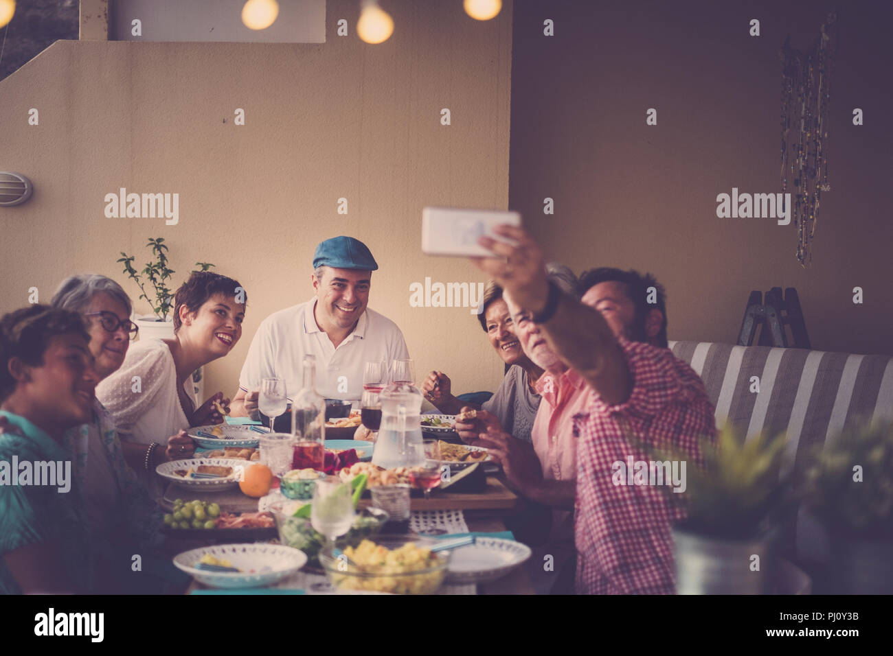 happy group of people in family friendship all together celebrating and having an outdoor nice dinner at home in the terrace. a man take selfie for al Stock Photo