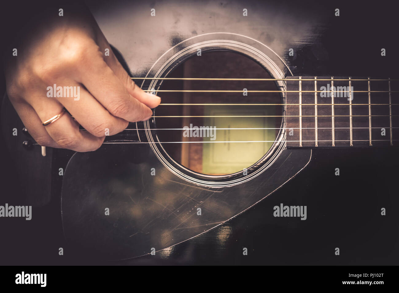 Guitarist Hand playing on acoustic guitar fretboard vintage style Stock Photo