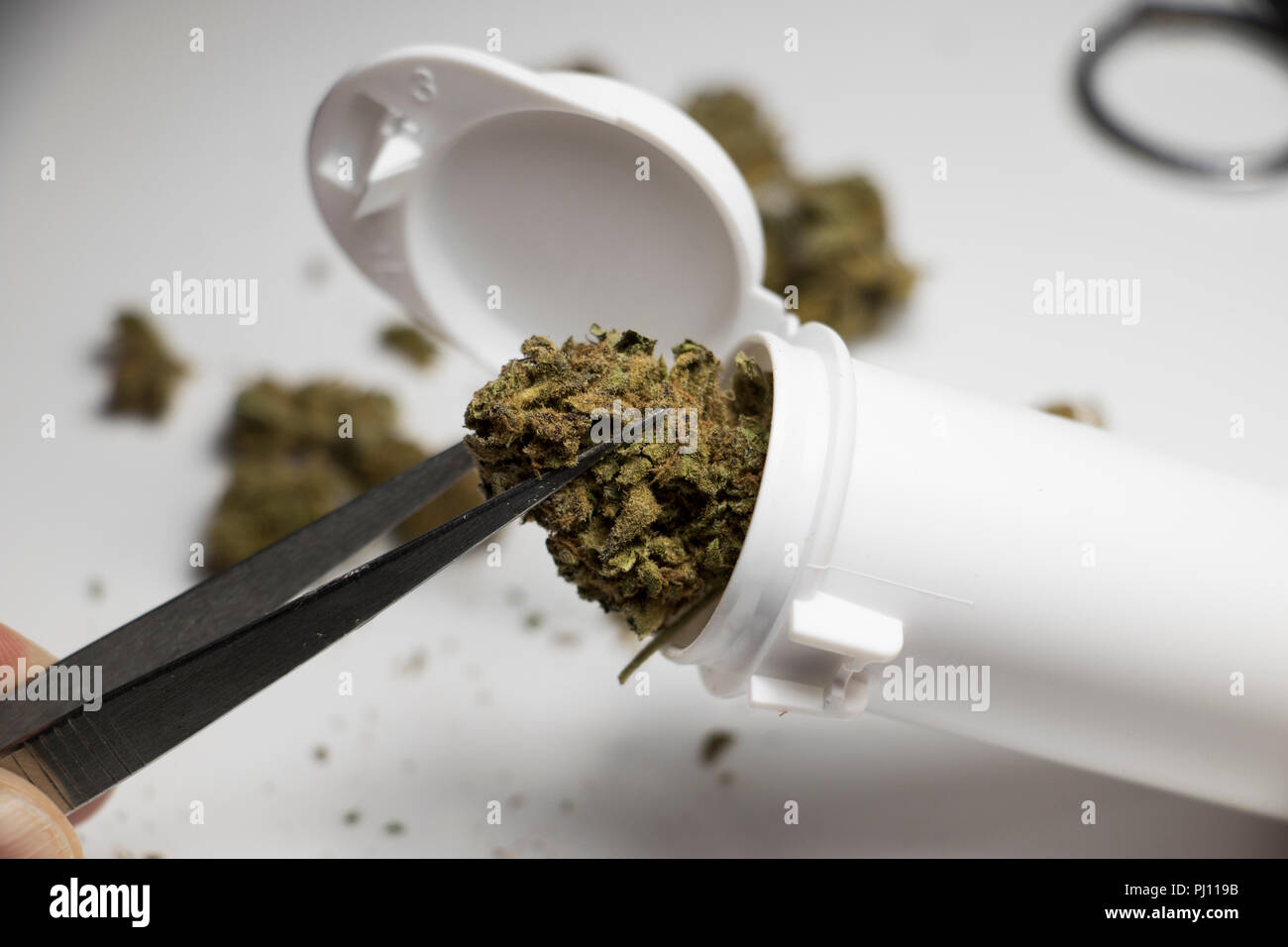 Bud of Mary Jane being pull out of a prescription bottle with tweezers