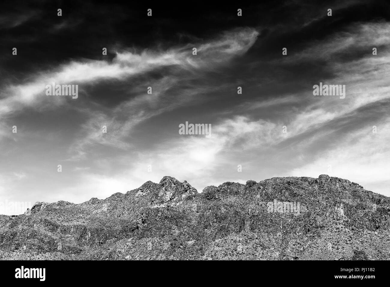 Barren desert mountains under cloudy sky, black and white. Stock Photo