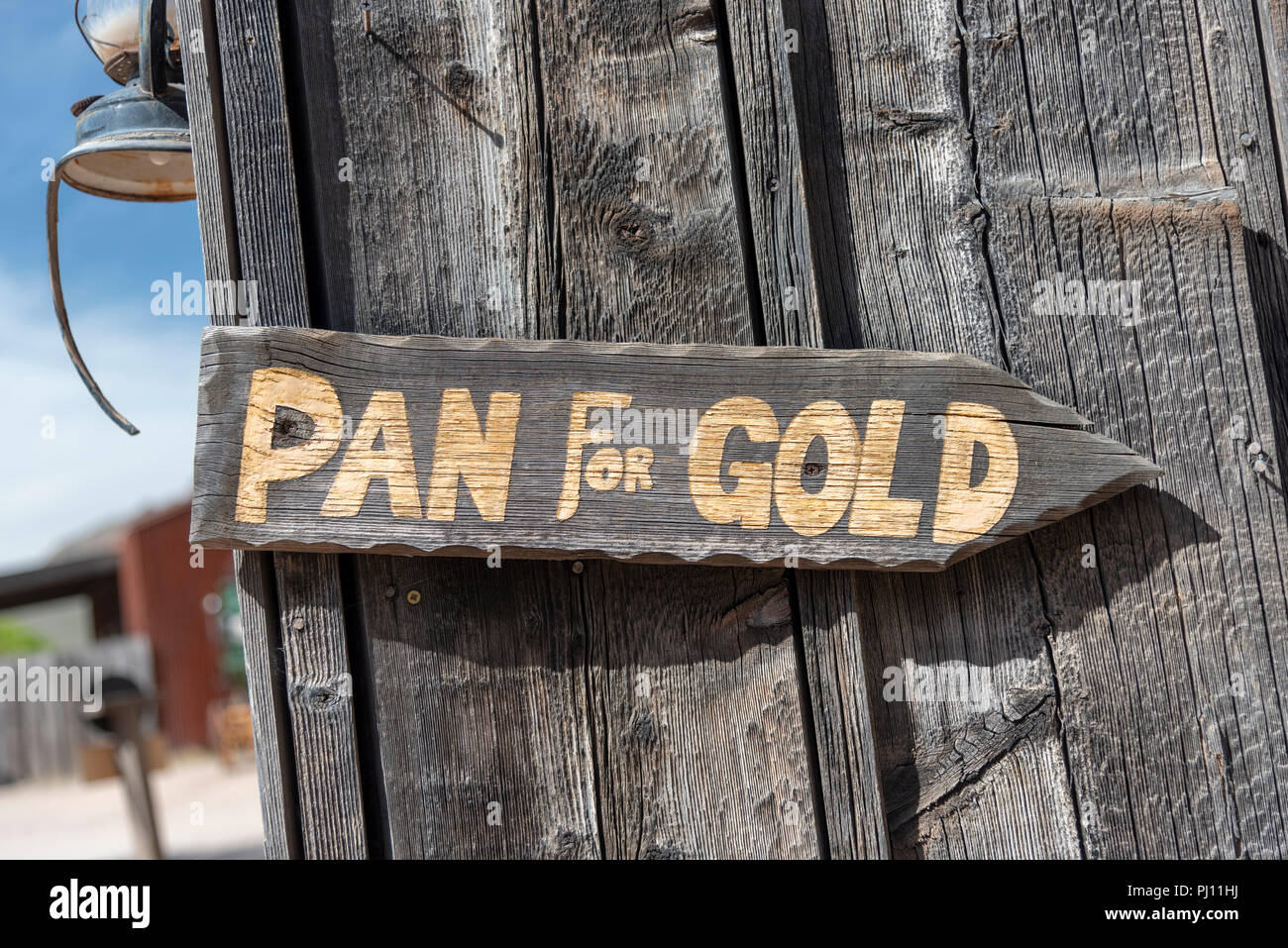 Old wooden sign “Pan For Gold” on old wooden wall. Gold letters. Stock Photo