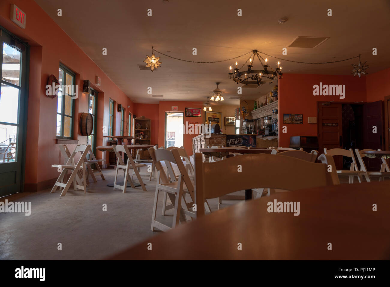 Restaurant with bar at end, interior, orange walls, white folding chairs and tables. Stock Photo