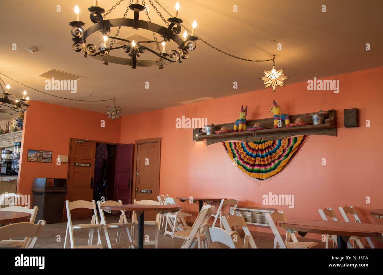 Interior of Restaurant and bar with folding chairs and western wall display, old candle style ceiling light fixture. Stock Photo