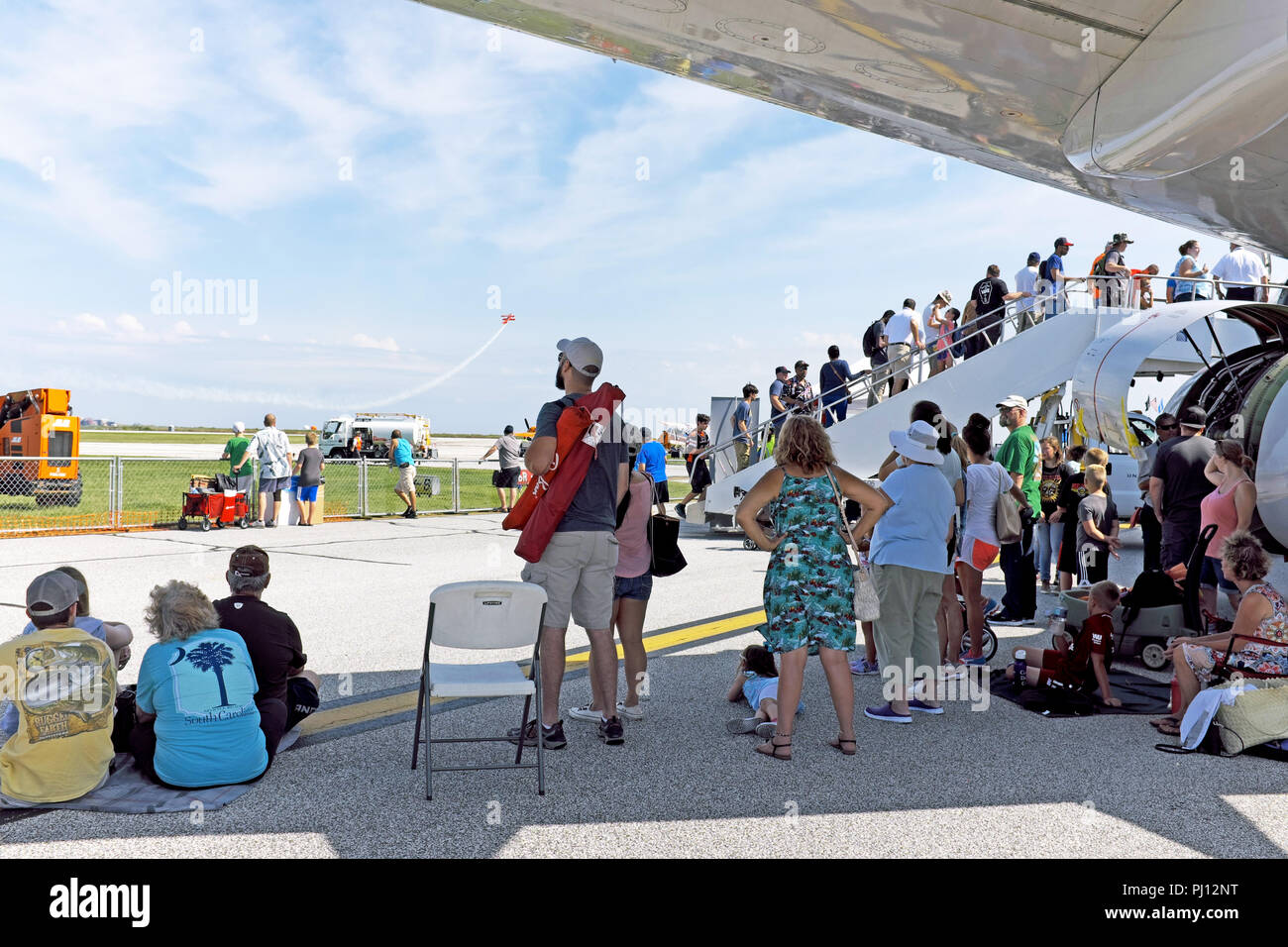People attending the 2018 Cleveland National Air Show take shade under the wing of a parked 737 airplane in Cleveland, Ohio, USA. Stock Photo