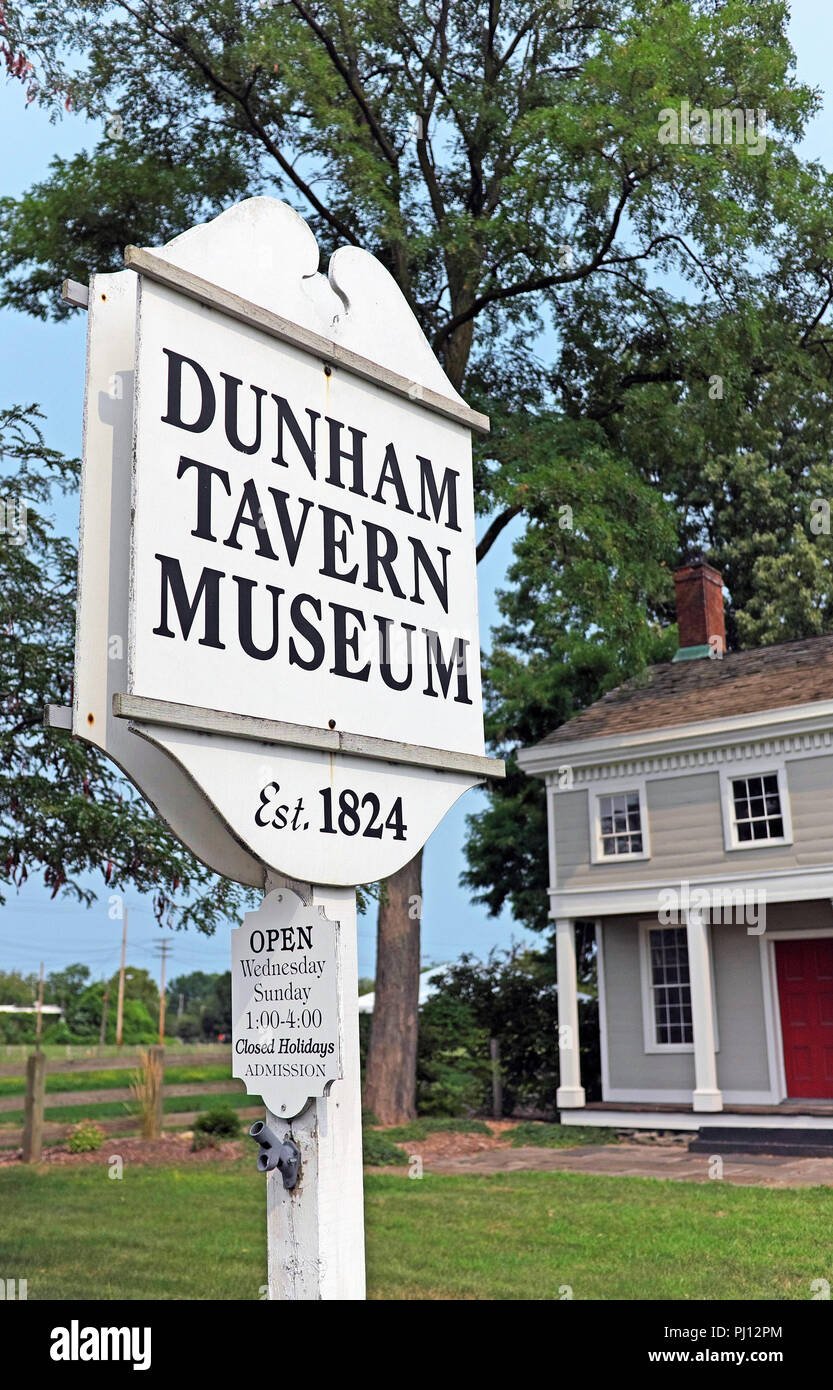 The Dunham Tavern Museum sign with opening hours posted in front of the stagecoach stop and tavern built in the early 1800s in Cleveland, Ohio, USA. Stock Photo