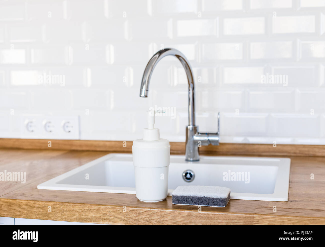 Clean kitchen. White sink, soap dispenser and sponge for washing dishes