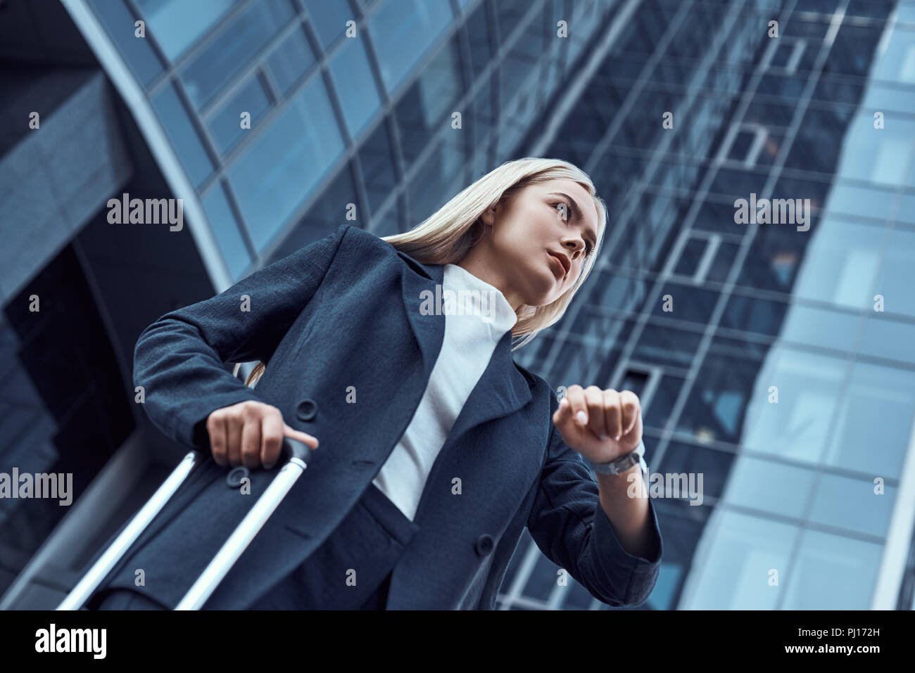 Woman looking at her wrist watch while going to office checking time on the city background Stock Photo