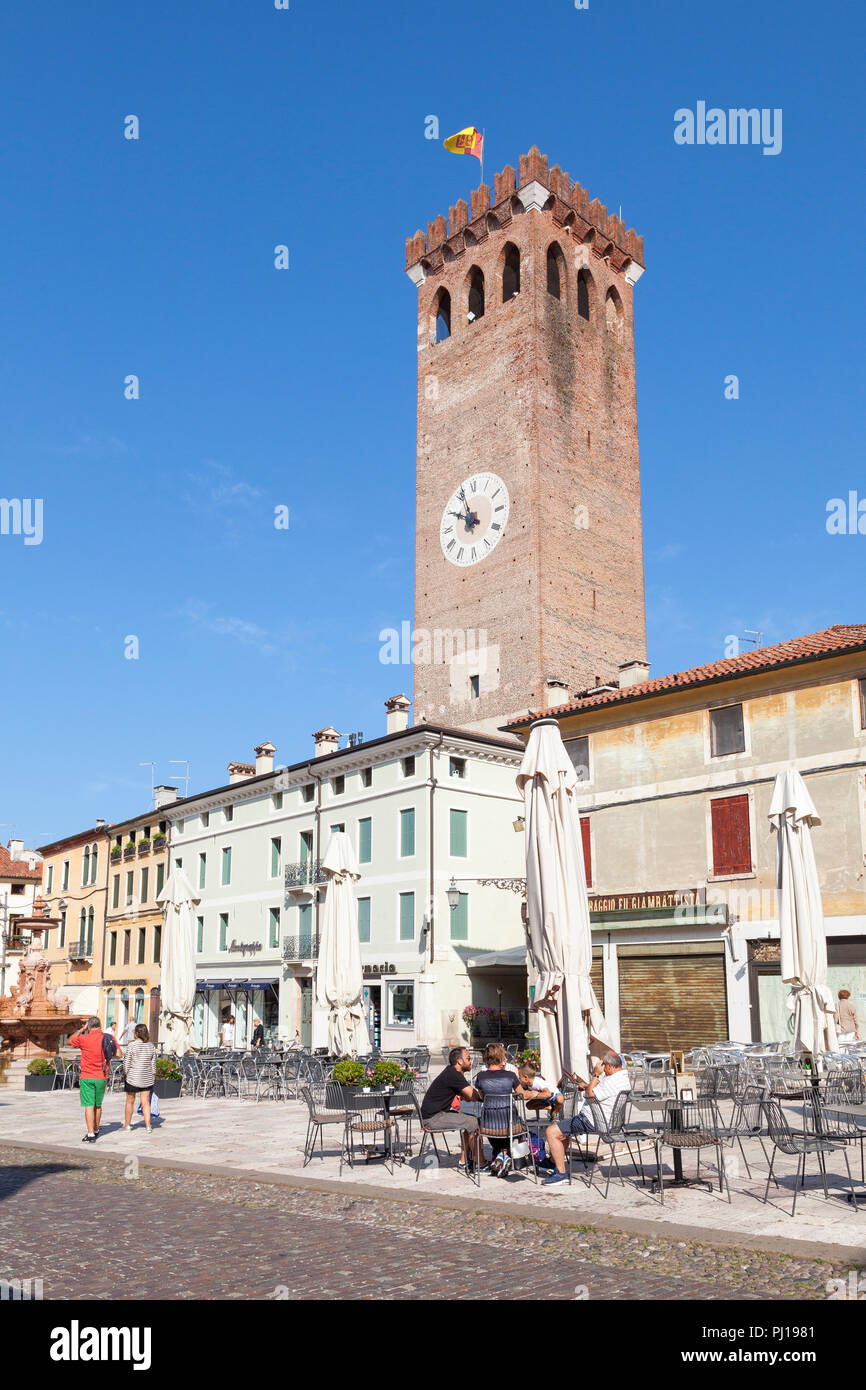 Medieval Civic Tower, Piazza Garibaldi, Bassano del Grappa, Vicenza, Italy with people seated at an outdoor table in the early morning before restaura Stock Photo