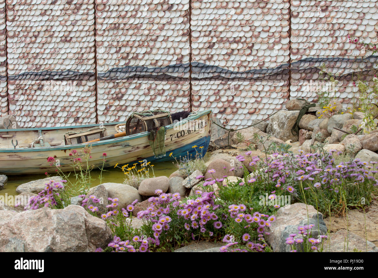 RHS Hampton Court Flower Show 2018, Show Garden representing a Galician secluded cove, traditional shell cladding, rustic boat and lobster pods. Stock Photo