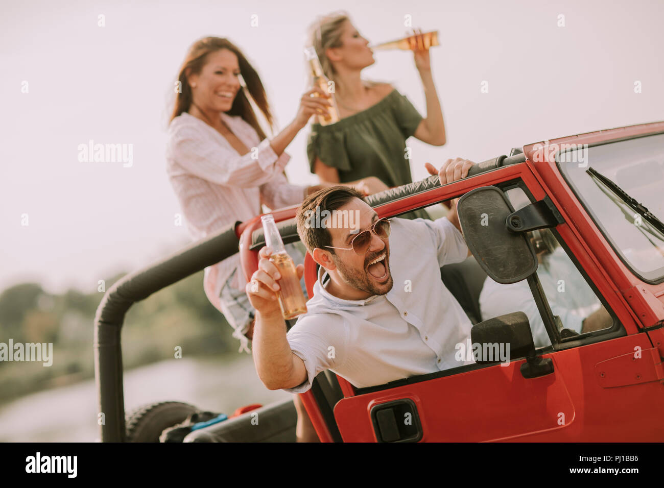 Young people having fun traveling together in convertible car and