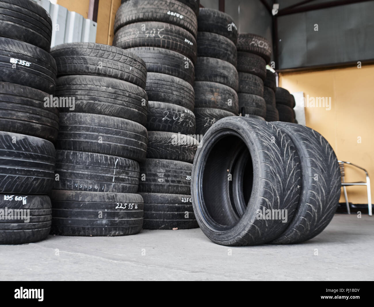 Used car tires stacked in piles at junkyard. Old wheels recycling and