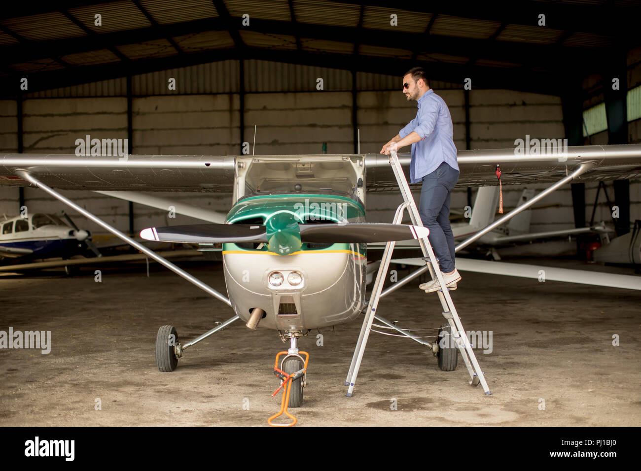 Handsome young pilot checking airplane  in the hangar Stock Photo