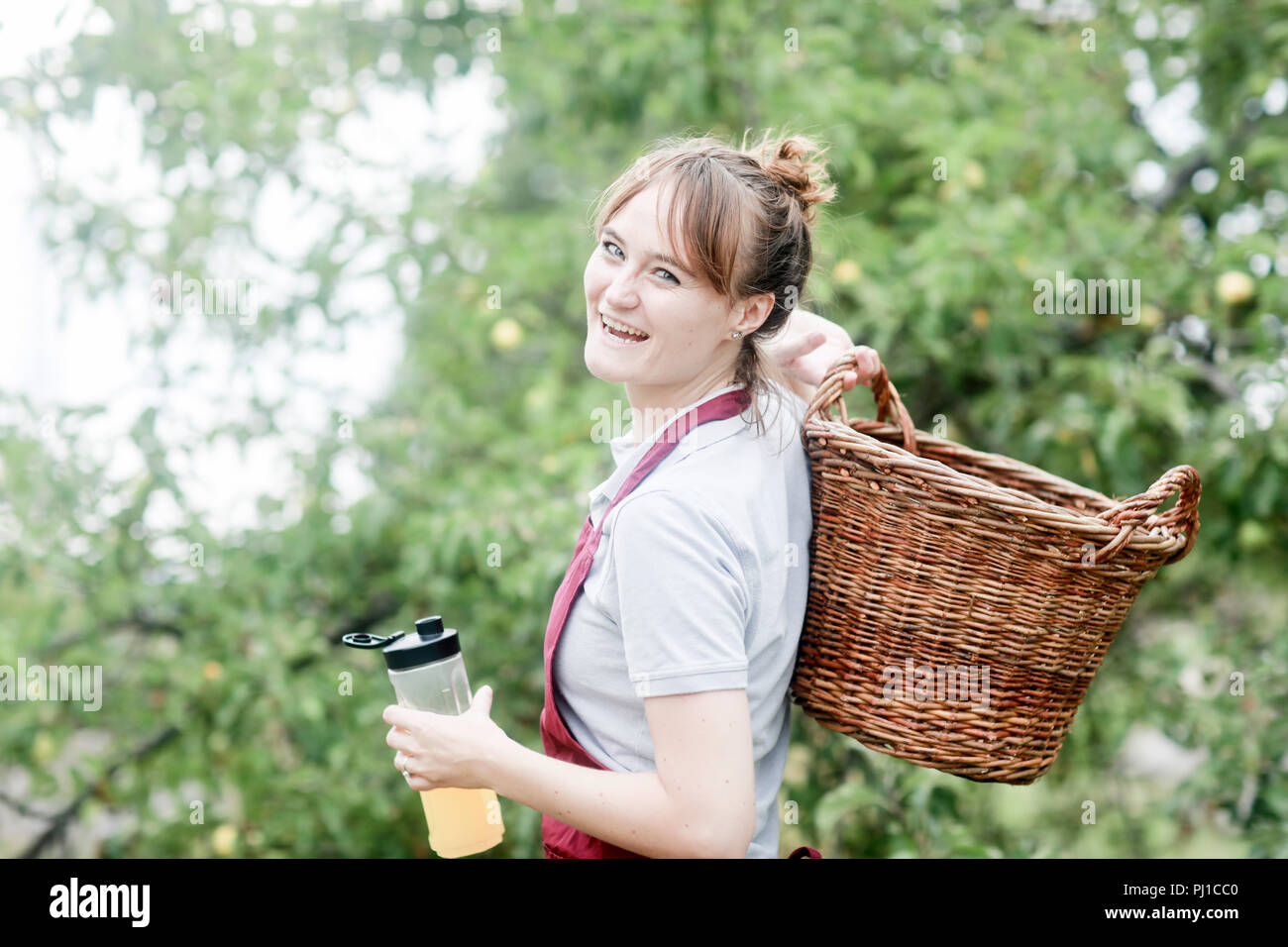 Smiling woman carrying a basket and juice drink, Germany Stock Photo