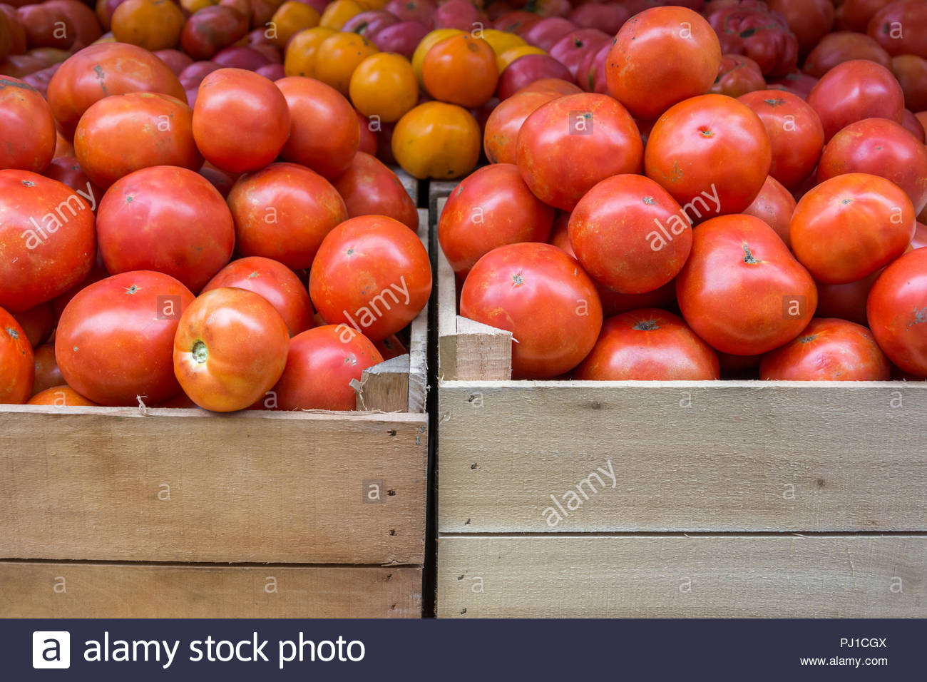 Fresh, ripe tomatoes in wood crates at a farmer's market. Stock Photo