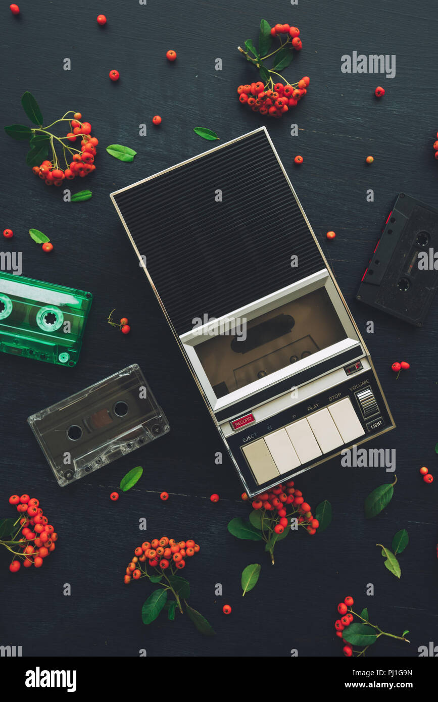 Flat lay music audio cassette and player, nostalgic image top view of retro technology from 80s and 90s with wild berry fruit decoration arrangement Stock Photo