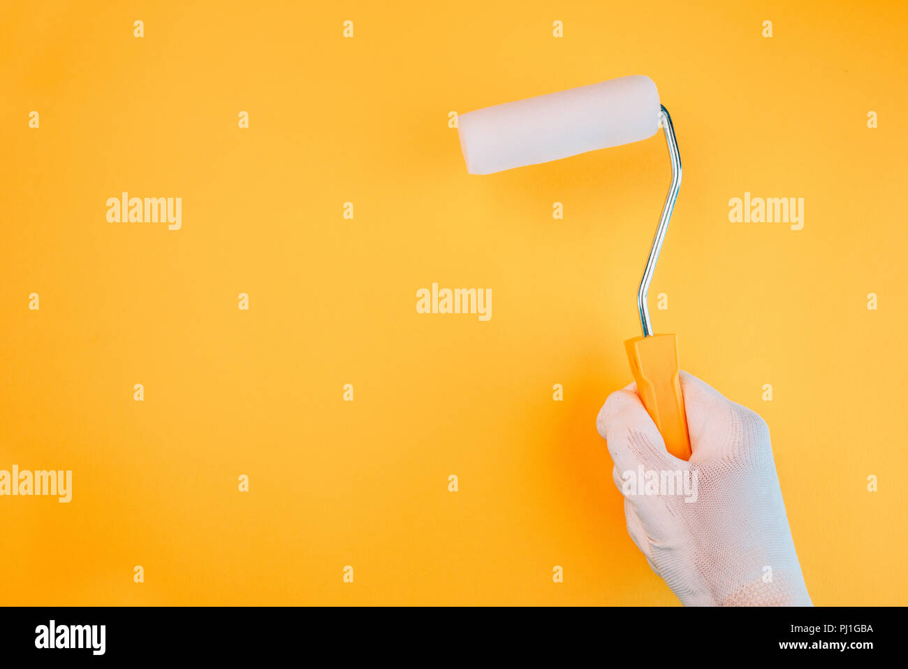 Hand with paint roller painting a wall in vivid warm colors Stock Photo