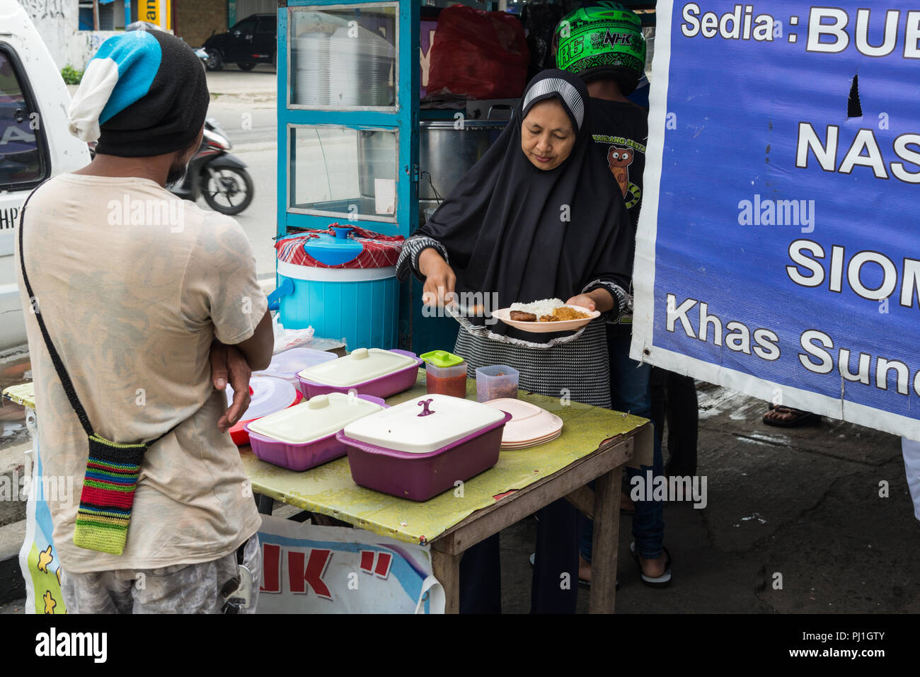 A woman serve food at a street side food stall. Sentani, Jayapura, West Papua, Indonesia. Stock Photo