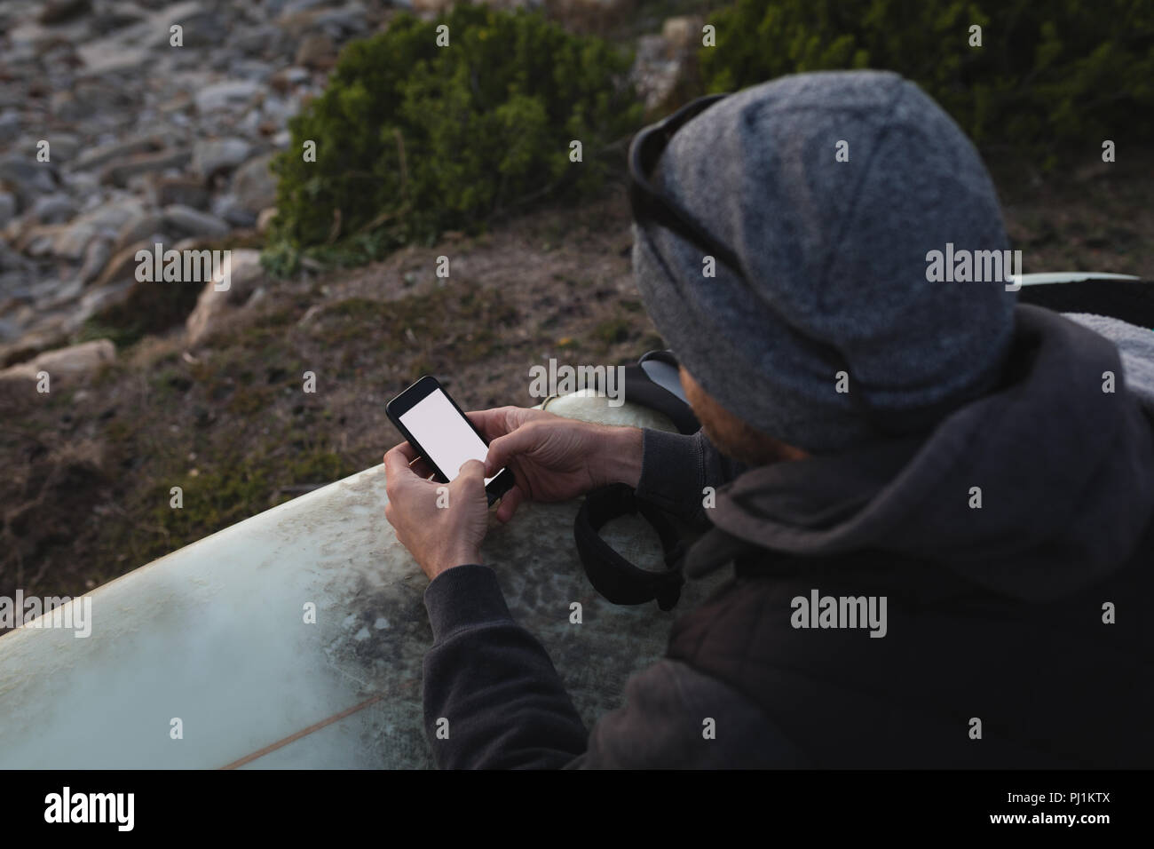 Man with surf board using mobile on the beach Stock Photo