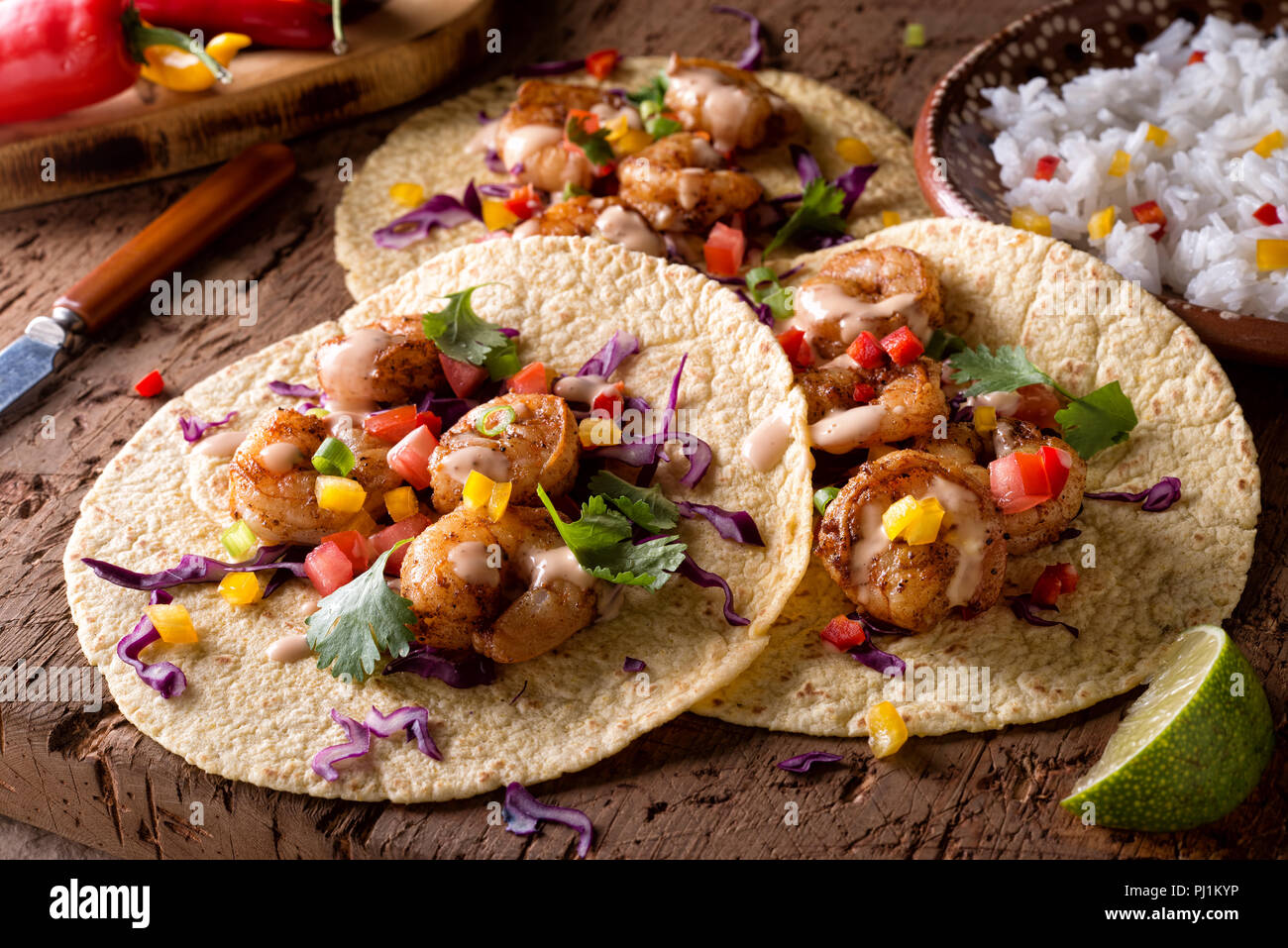 Delicious spicy shrimp tacos with sriracha mayo on a rustic wood table top. Stock Photo