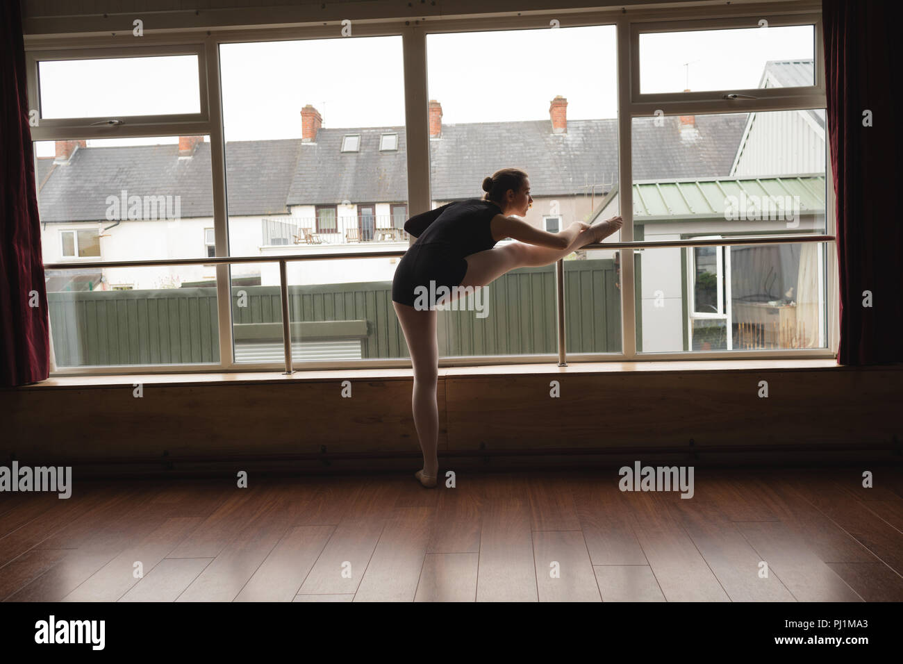 Ballerina stretching on barre while practicing ballet dance Stock Photo