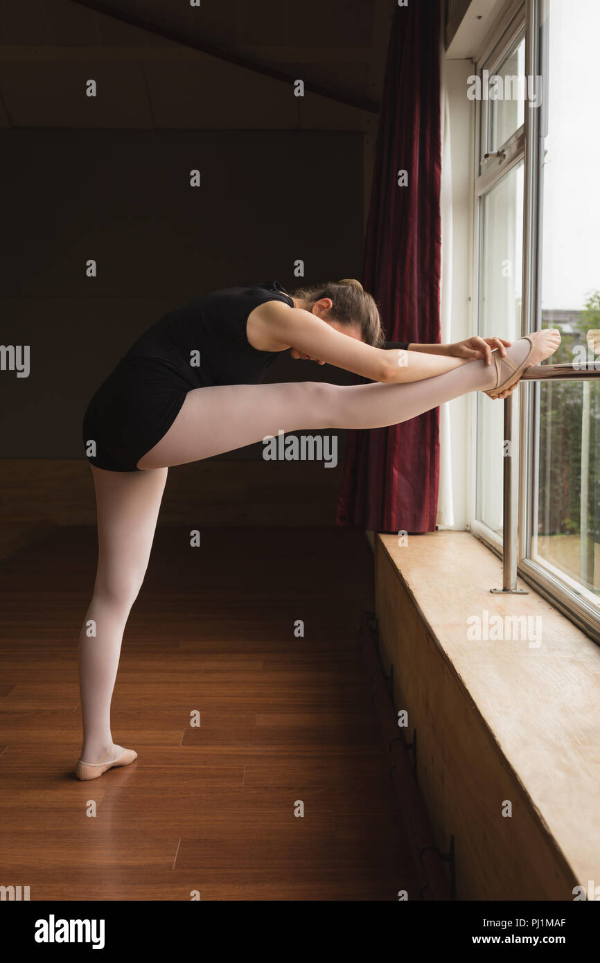 Ballerina stretching on barre while practicing ballet dance Stock Photo