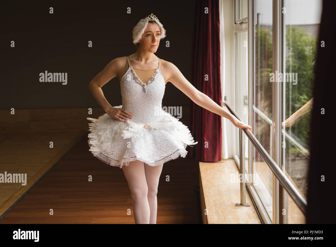 Ballerina looking through window in dance studio Stock Photo