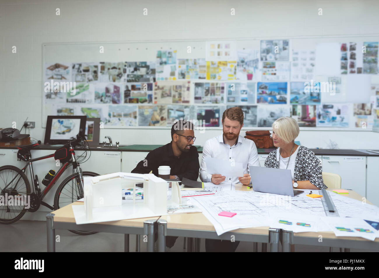 Executives discussing over blueprint at desk Stock Photo