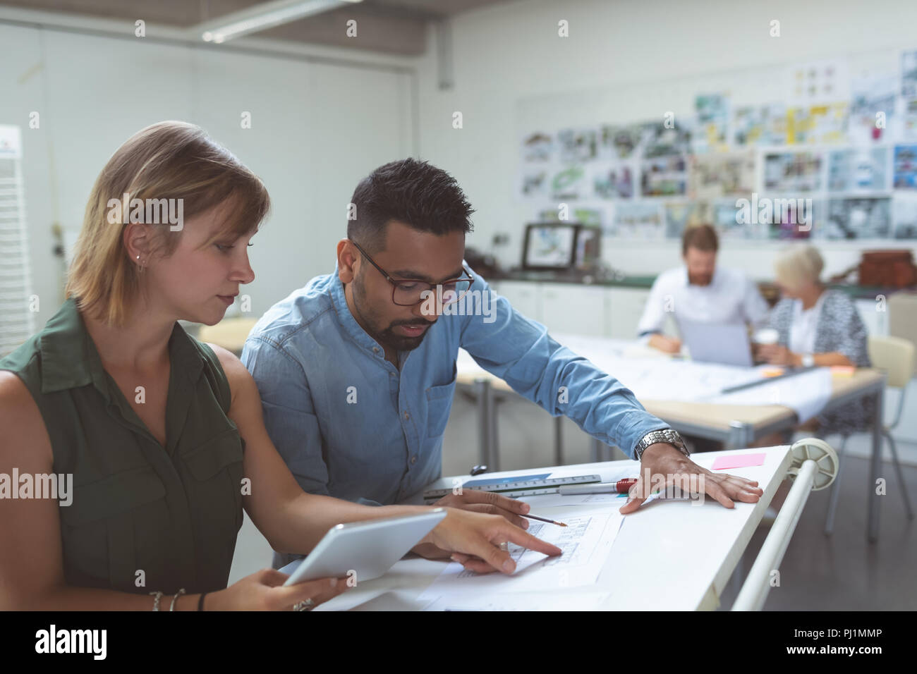 Executives discussing over blueprint on drafting table Stock Photo
