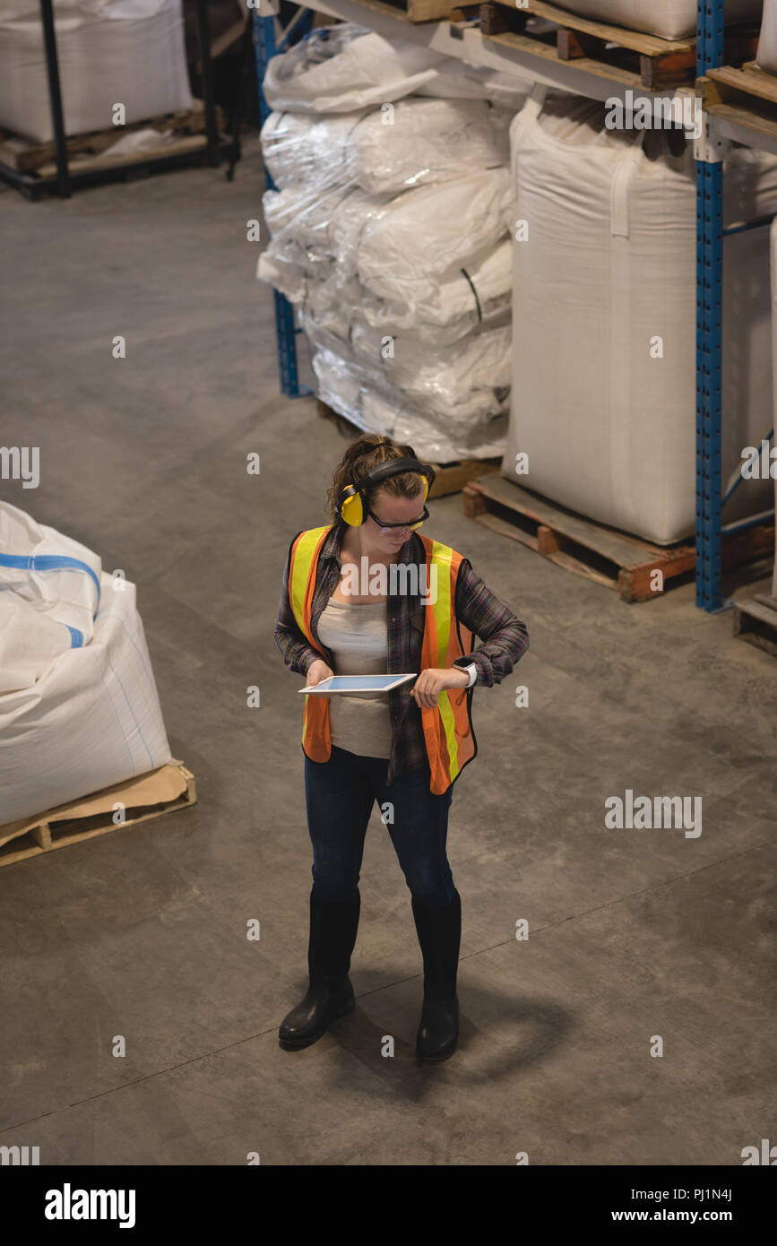 Female worker checking time while using digital tablet Stock Photo