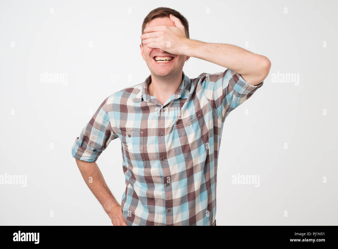 Portrait of a young smiling man covering his eyes with his hand Stock ...