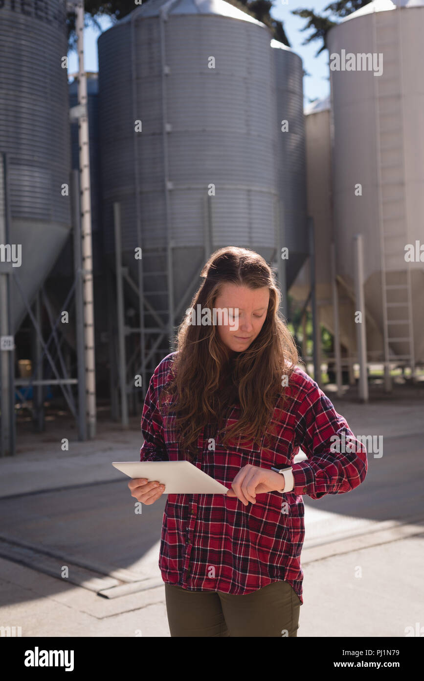 Female worker checking time while using digital tablet Stock Photo
