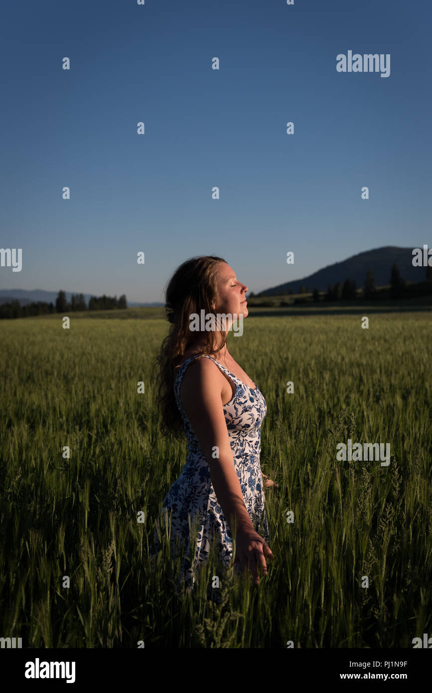 Woman standing with eyes closed in the field Stock Photo - Alamy